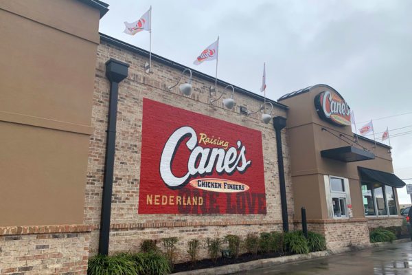 side of raising canes with sign, landscaping and flags