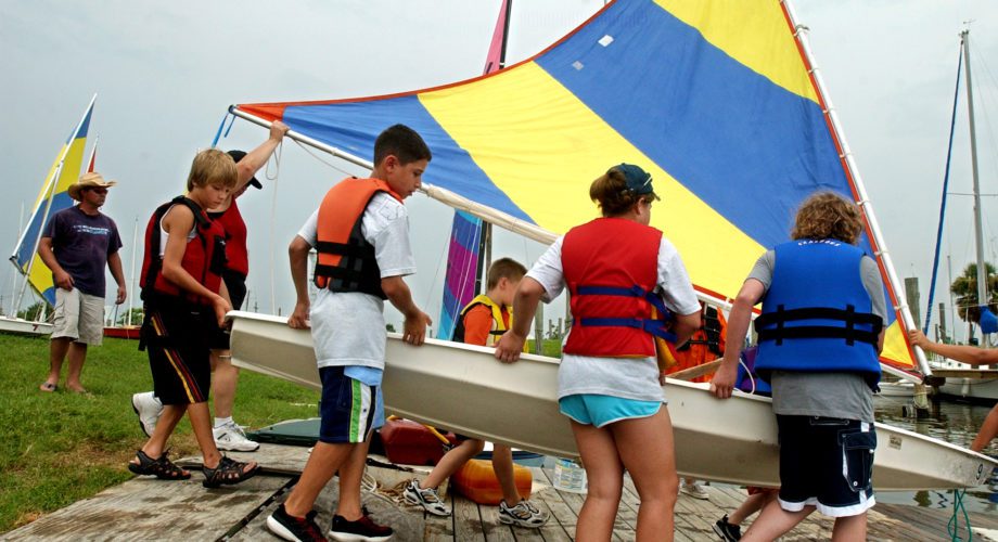 Students carry a sailboat onto a ramp at Pleasure Island Marina