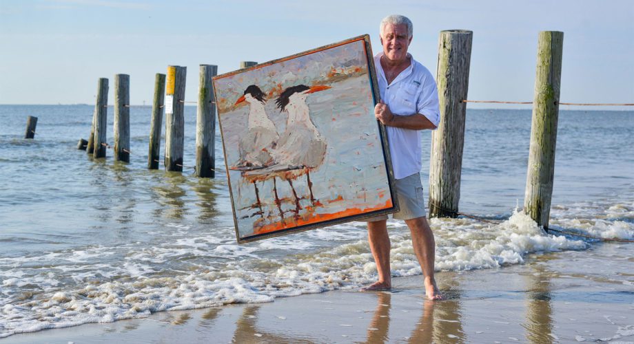 Joey standing on the beach with his painting