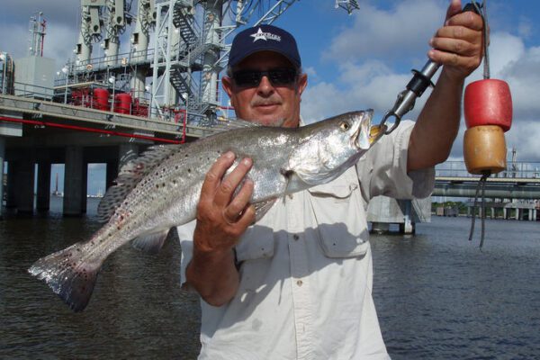 man holding speckled trout near the rigs in port arthur texas