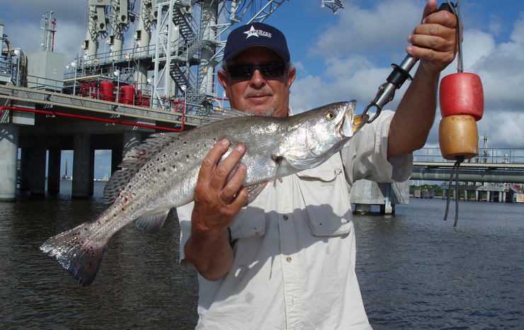 man holding speckled trout near the rigs in port arthur texas