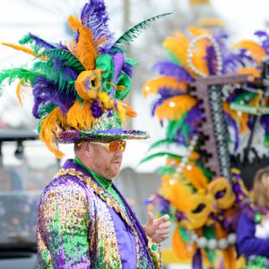 Man walking in a costumed parade handing out beads