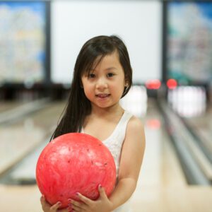 little girl holding a bowling ball inside max bowl in port arthur texas