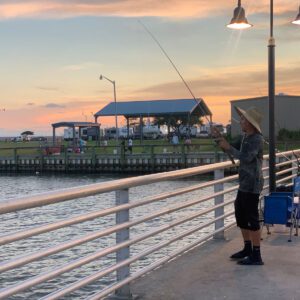 man fishing at sunset on the lighted pier at walter umphrey state park on pleasure island in port arthur