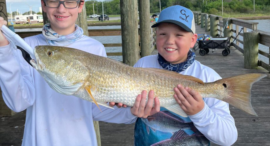 two boys showing off their redfish catch on the pleasure island fishing pier in port arthur texas