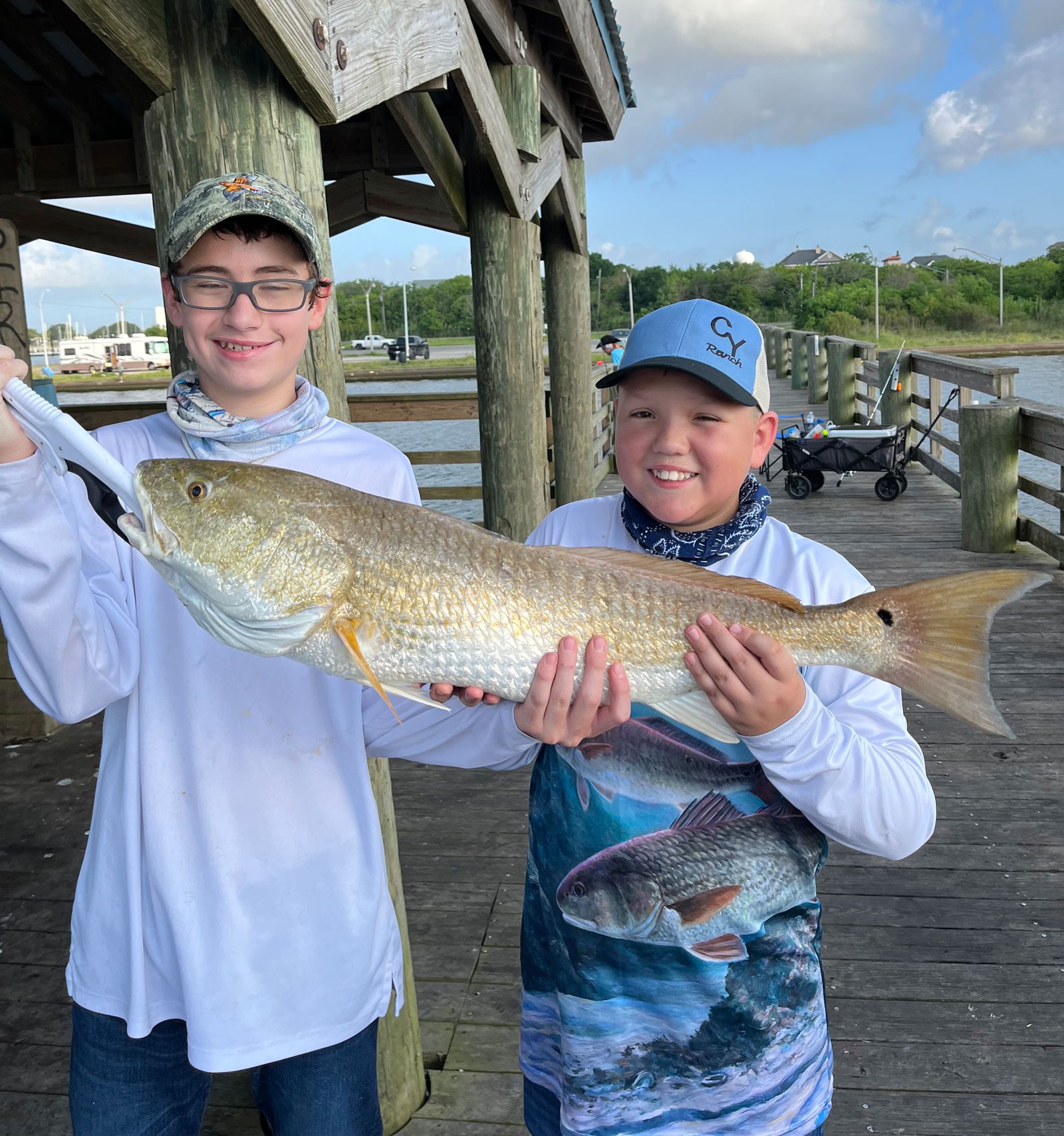two boys showing off their redfish catch on the pleasure island fishing pier in port arthur texas