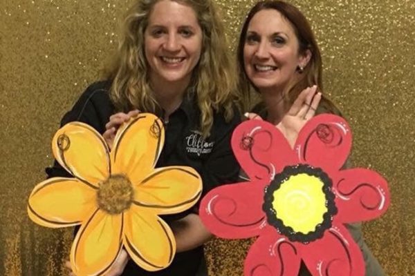two women holding flower paintings