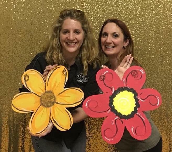 two women holding flower paintings