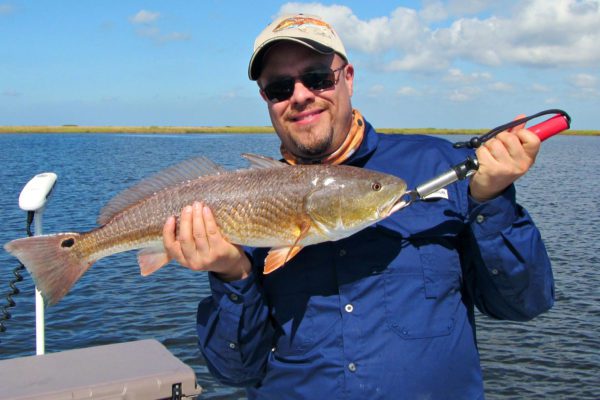 man holding up a redfish on sabine lake in port arthur, texas