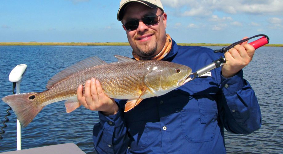 man holding up a redfish on sabine lake in port arthur, texas