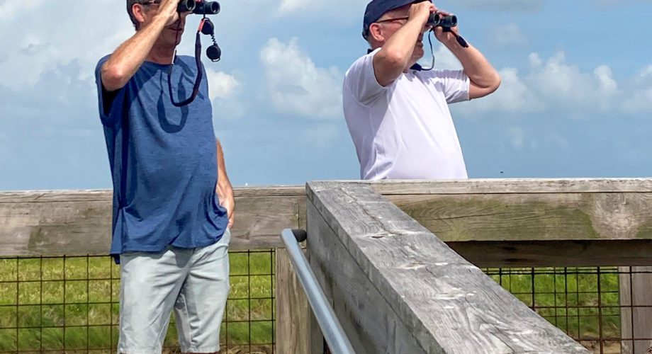 men looking through binoculars on a sea rim state park boardwalk in port arthur