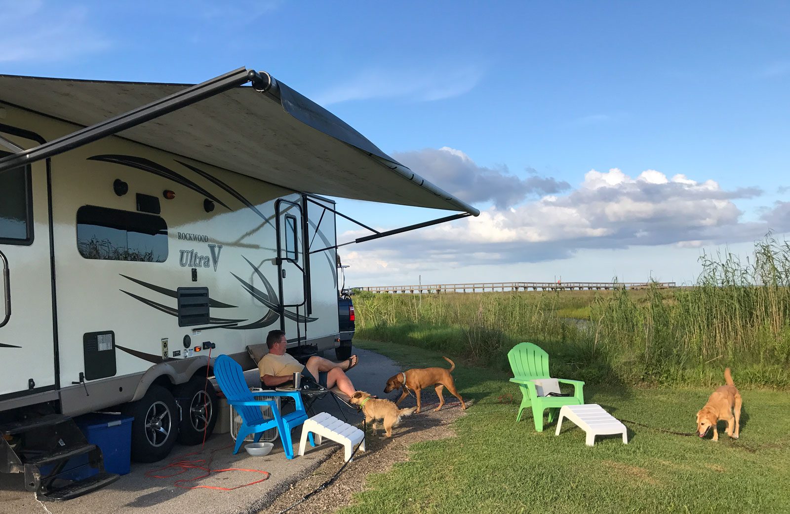 a man sitting next to his rv with his dogs at sea rim state park in port arthur texas