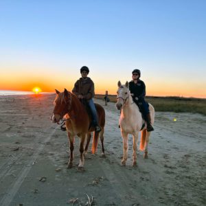 two women on horseback at the beach at sunset at sea rim state park in port arthur, texas