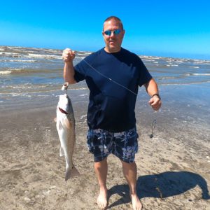 man holding a redfish while shore fishing at sea rim state park in port arthur, texas