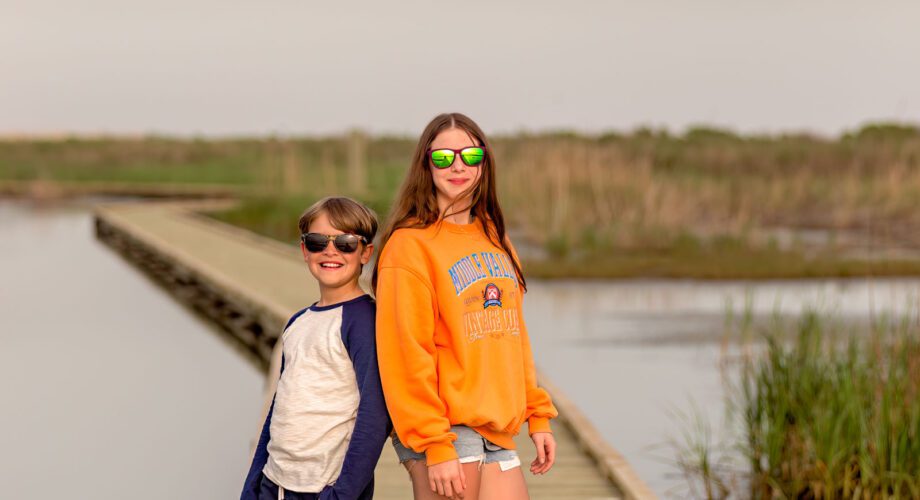 two kids posing on a boardwalk surrounded by water in port arthur texas