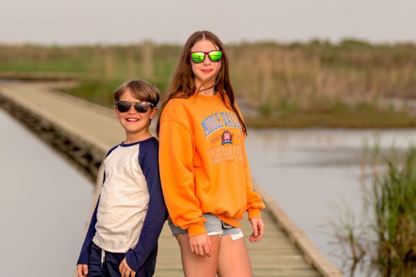 two kids posing on a boardwalk surrounded by water in port arthur texas