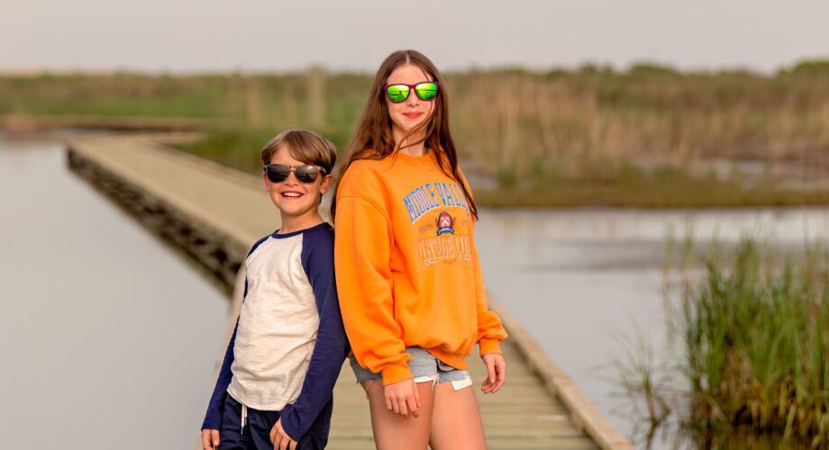 two kids posing on a boardwalk surrounded by water in port arthur texas