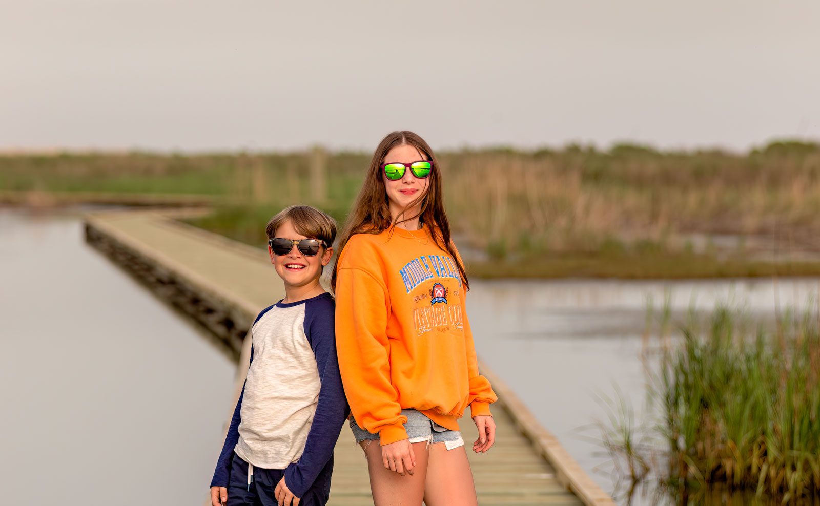 two kids posing on a boardwalk surrounded by water in port arthur texas