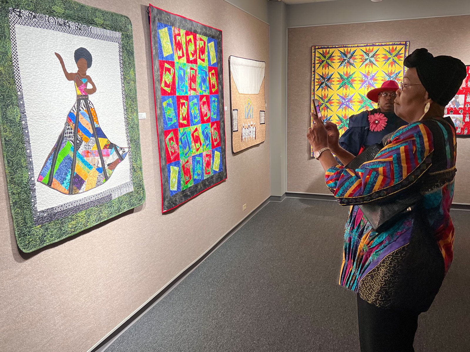 woman taking a photo of a colorful african american quilters association quilt at the museum of the gulf coast in port arthur