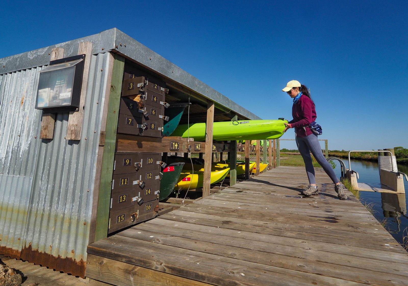 girl renting a kayak at sea rim state park's rental kiosk on the marsh unit