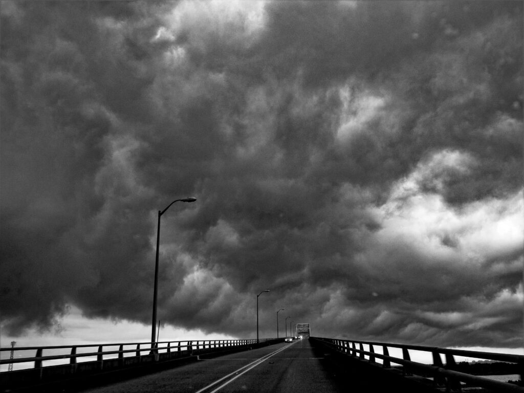 black and white photo of the pleasure island bridge and clouds in port arthur texas