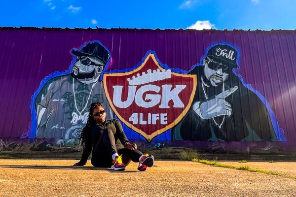 a girl poses in front of the ugk mural in downtown port arthur texas