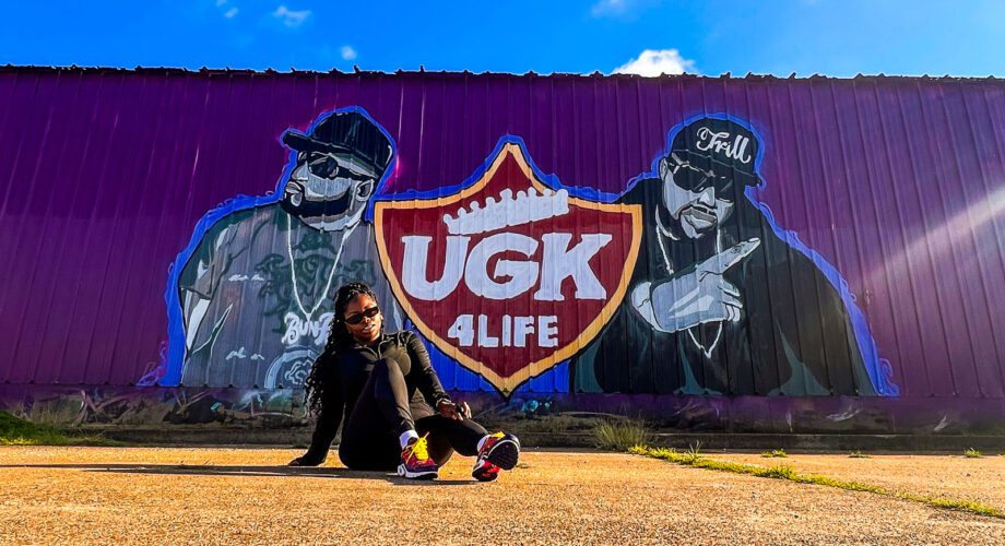 a girl poses in front of the ugk mural in downtown port arthur texas