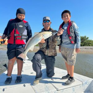 three guys holding a redfish on sabine lake in port arthur texas