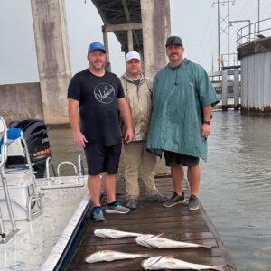 three guys posing with their catch on the dock in the channel in port arthur texas