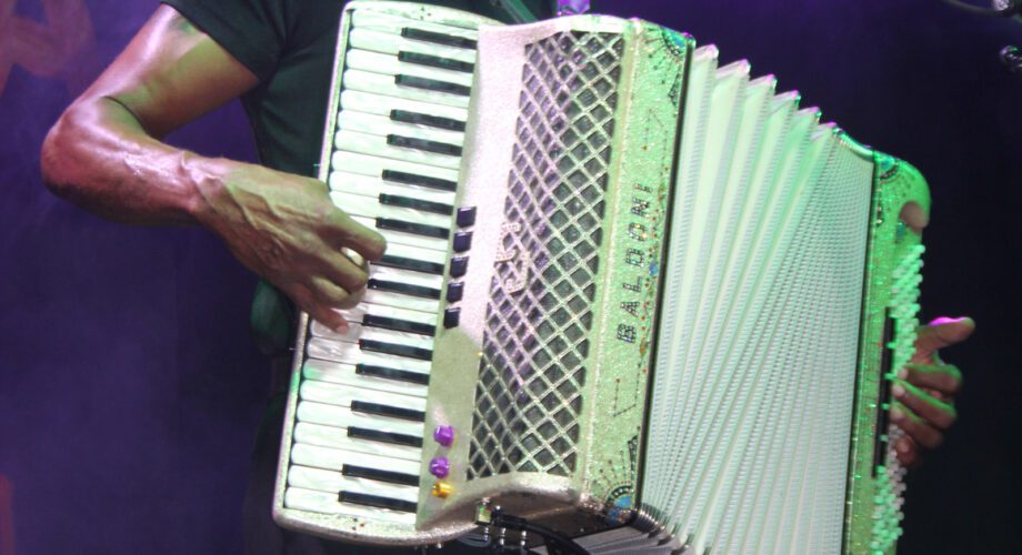 Cj Chenier plays accordion while singing at the mic