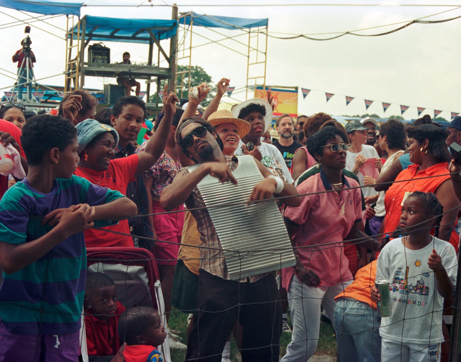 man playing a washboard surrounded by a happy crowd listening to zydeco music