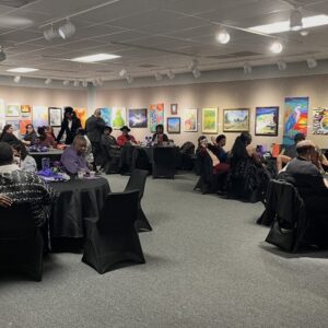 Museum of the Gulf Coast Meeting Space in gallery with black tablecloths and a woman in yellow dress.