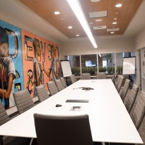 big white table with multiple chairs and a colorful mural on wall