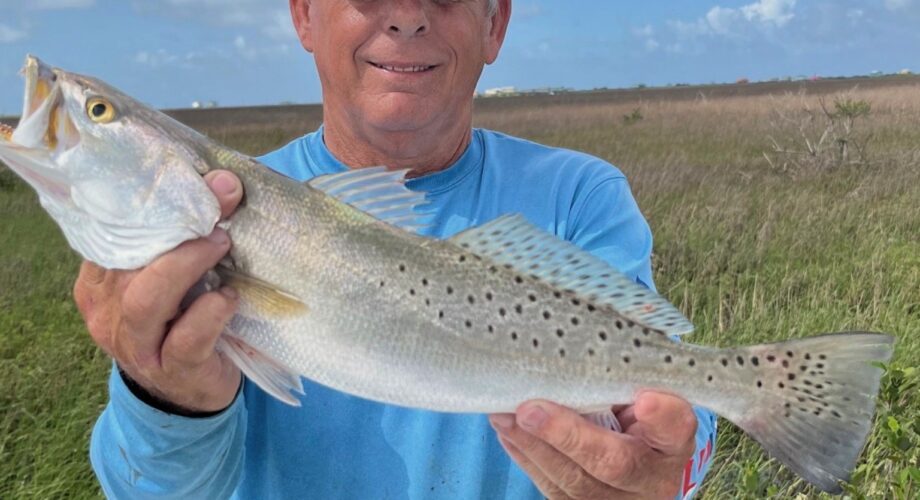 Southeast Texas Fishing Classic man in blue shirt holds fish in marsh.