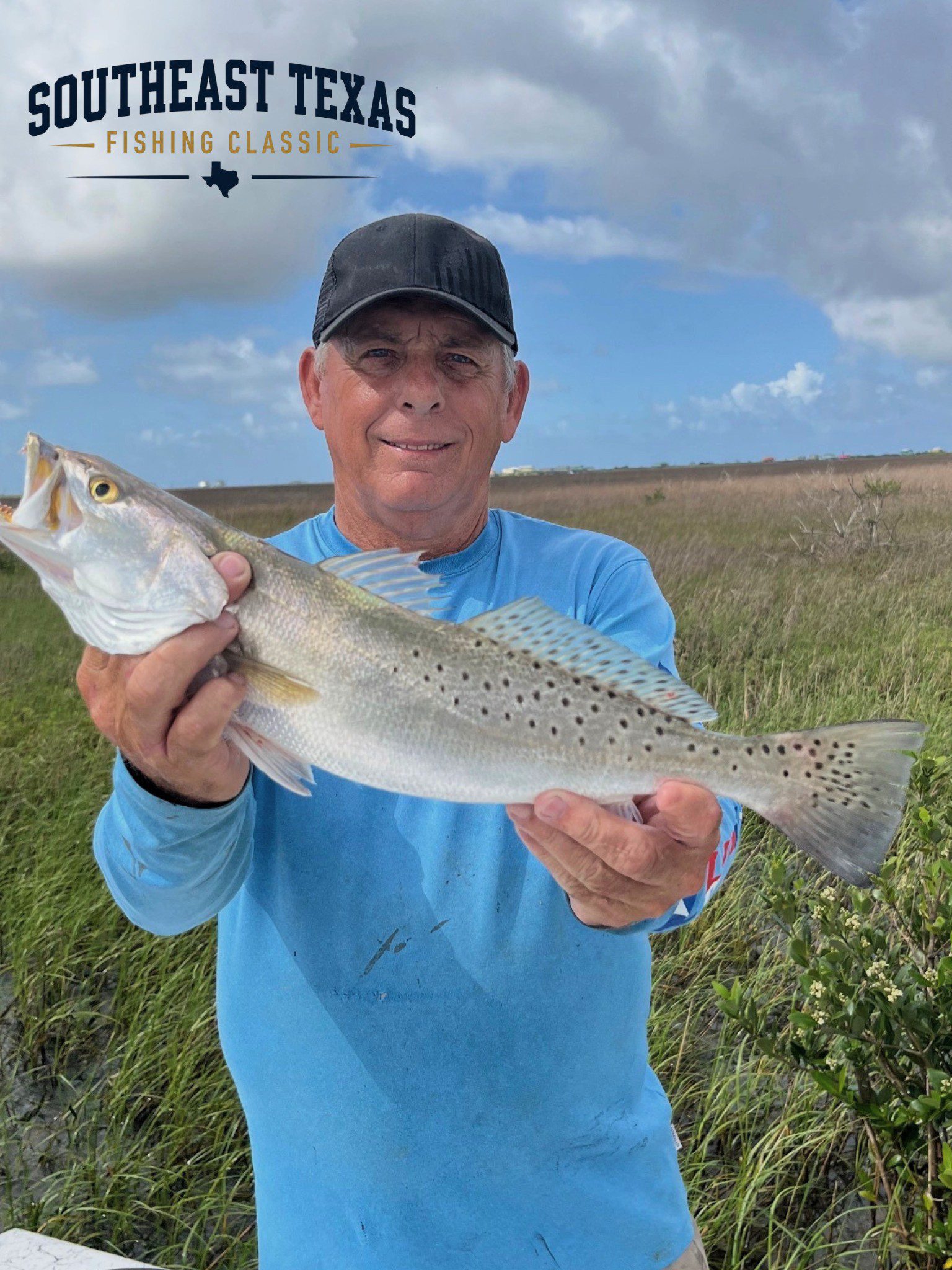 Southeast Texas Fishing Classic man in blue shirt holds fish in marsh.
